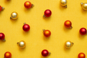 Christmas ornament. red orange gold baubles on yellow fabric texture background. top view