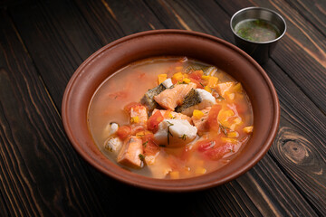 Ukha royally, fish soup, from several varieties of fish, in a clay plate, on a wooden board