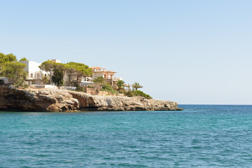 Fototapeta na wymiar Private Mediterranean coastal villas looking onto calm turquoise water on a sunny summer day