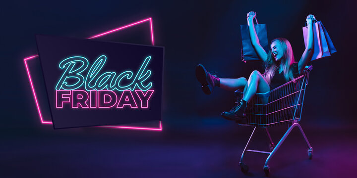 Laughting, shopping. Portrait of young woman in neon on dark studio backgound. Human emotions, black friday, cyber monday, purchases, sales, finance concept. Copyspace. Seamless post for instagram.