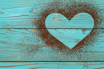 Heart shape of spreading cocoa powder on blue wooden background