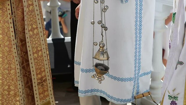 The priest holds a censer with burning incense in his hands.
