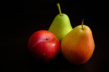 Colorful pear and plum in dark background