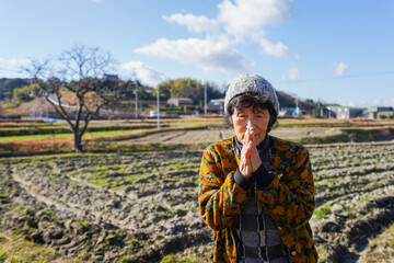 田舎でお祈りをする高齢の女性