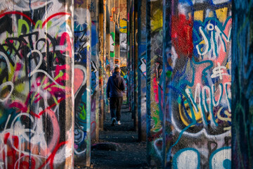 A Man In-Between A Row of Graffiti Covered Walls at Graffiti Pier