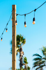 Obraz premium Line of light bulbs lighting the way to a terrace on the beach