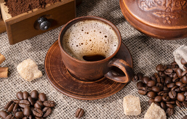 ceramic cup with coffee, sugar and beans on sacking