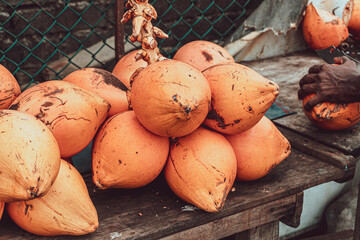 Pomarańczowe owoce kokosowe, kokos na ulicy podczas cięcia.
