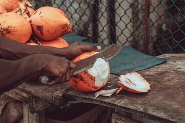 Pomarańczowe owoce kokosowe, kokos na ulicy podczas cięcia.