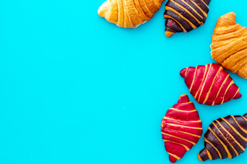 Set of croissants - chocolate, berry, classic - on blue table top view