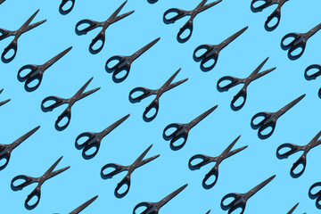 Open and closed black stationery scissors on a blue background. Pattern with stationery scissors. The concept of office supplies, school, student body, needlework.