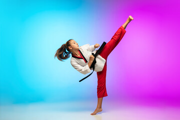 Powerful. Karate, taekwondo girl with black belt isolated on gradient background in neon light....