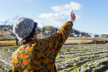 田舎で上を指差す高齢の女性
