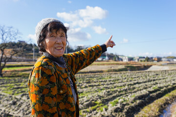 田舎で上を指差す高齢の女性