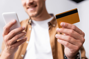 Cropped view of businessman holding credit card and using smartphone