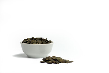bowl of peeled pumkin seeds and a pile of seeds isolated on white background