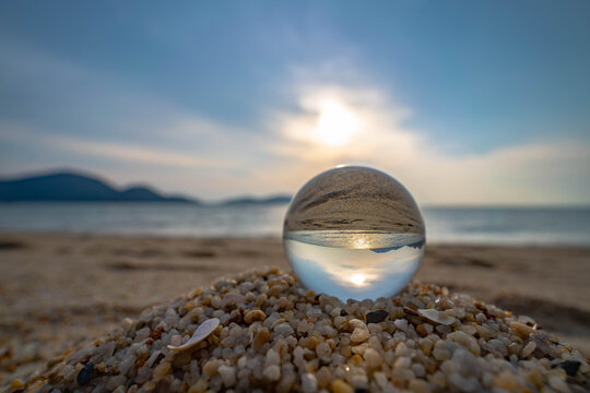 Close-up of glass ball in beautiful sunset beach with bokeh background