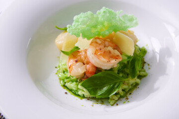Delicious risotto with spinach, greens and prawns. Served in a modern dishware. Shallow dof