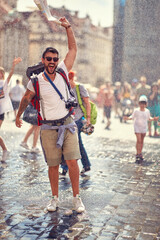 Young male tourist enjoying the fontaine shower at the city square