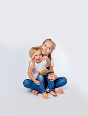 cute boy in jeans and a t-shirt sits with an older sister