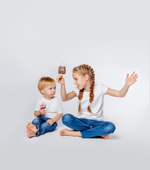 cute brother and sister in blue jeans and t-shirts eat ice cream