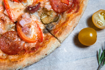 Appetizing pizza on a wooden table surrounded by herbs and spices. The concept of delicious food, restaurants and cafes