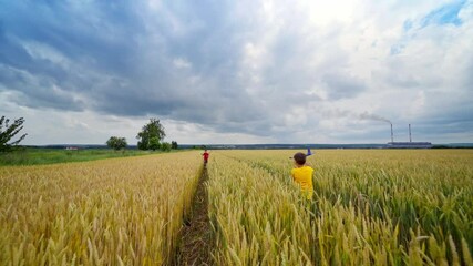 Children having fun on agricultural field. Boys launching toy planes in farmland in summer day. Happy childhood.