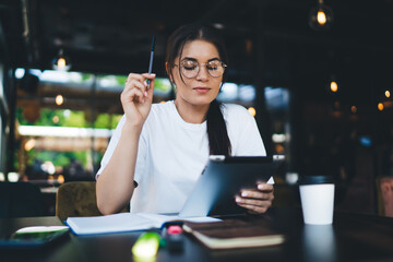 Thoughtful young woman with tablet in cafe