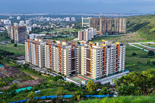 Aerial image of tall buildings under construction near hill in Pune, Maharashtra.