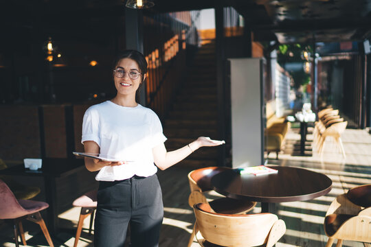 Cheerful young businesswoman in cozy restaurant with tablet