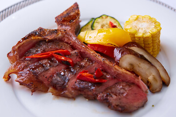 grilled steak tee bon with spices on white plate. Delicious restaurant food. Shallow dof.