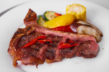 grilled steak tee bon with spices on white plate. Delicious restaurant food. Shallow dof.