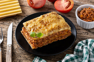 Piece of meat lasagna on black plate on rustic wooden table