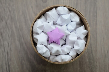 lucky origami stars with violet star in cardboard jar, box