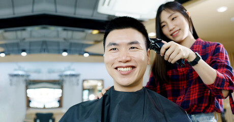 Happy Asian man use the haircut service in Barber shop. Woman hairdresser provide service mind. Hairdressing equipment is clean. End of quarantine and return to open salon hair work