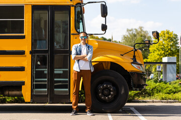 A happy male teacher near school bus