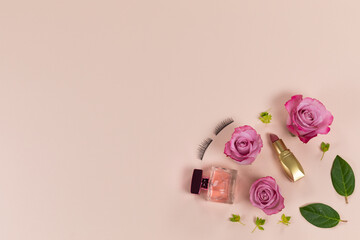 View of a make up with perfume and pink flowers lying on pink background