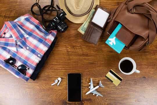 View of a variety of essential travelling items with tablet, smartphone and camera on wooden table