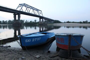 evening urban rural landscape two boats by the river under the bridge on a cloudy day