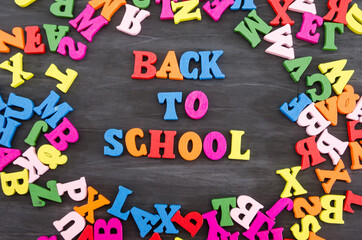 the word "back to school" is made up of colored letters on a black wooden background. Schloll concept.