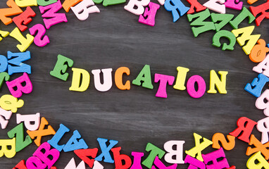 the word "education" is made of colored letters on a black wooden background. Schloll concept. Back to school.