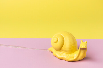 Snail leaving slime trail on the vibrant pink yellow background. Minimal abstract concept. Flat lay.