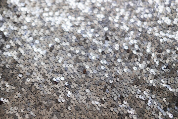 Sequin fabric texture. Shiny silver sparkling background. Clothing piece of glitter metallic for a glamorous party, celebration. Close-up.