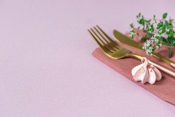 Pink meringue, knife and fork and linen napkin on a pink background. Celebration.