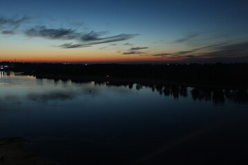 Obraz premium Sunset over the river blue and red sky stars and trees forest reflected on the water