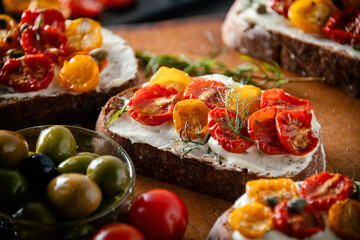 Sliced bread with cream cheese and homemade dried tomatoes on wooden board.Delicious snack.

