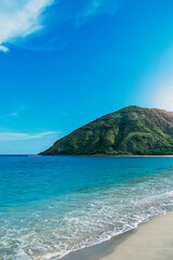 Fototapeta premium Mar verde y azul transparente con una montaña de fondo