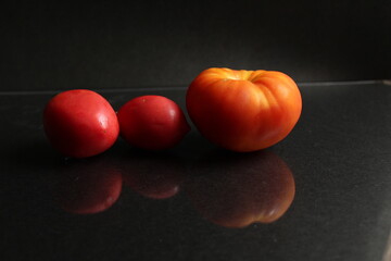 three red yellow tomatoes lie on a black background side view food background with copy space