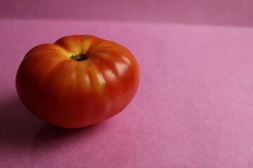red large tomato vegetable food lying on pink background with copy space
