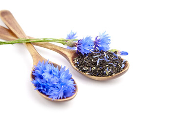 Herbal and black tea blend in spoons with fresh cornflowers isolated on white